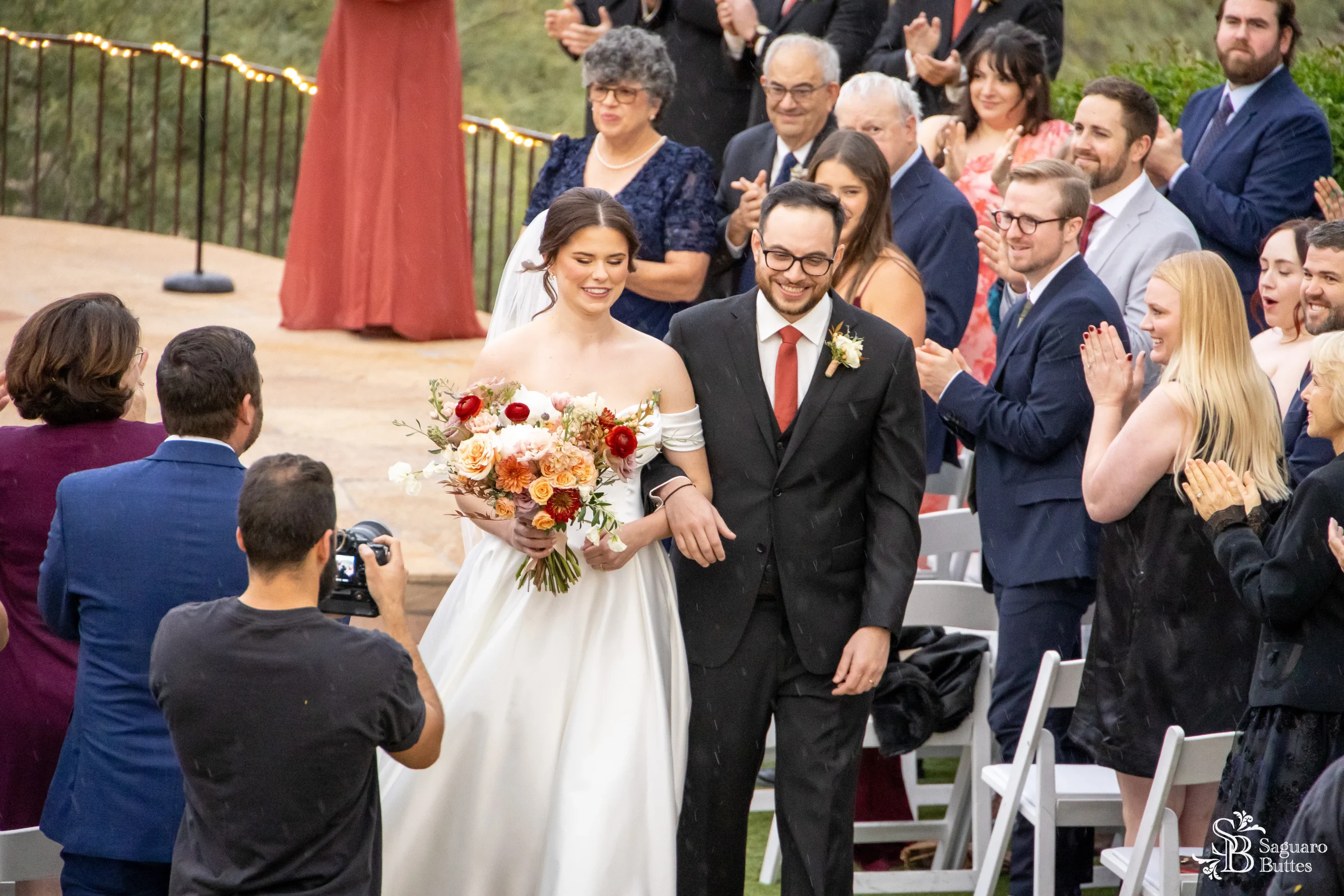 Newlyweds walk down the aisle with a joyful crowd applauding.